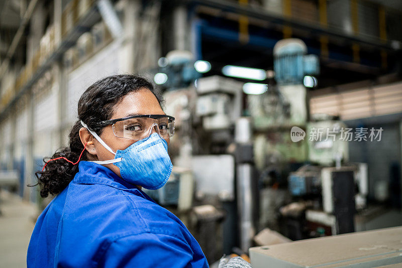 图为一位中年妇女在工厂/工业中工作，戴着防护口罩